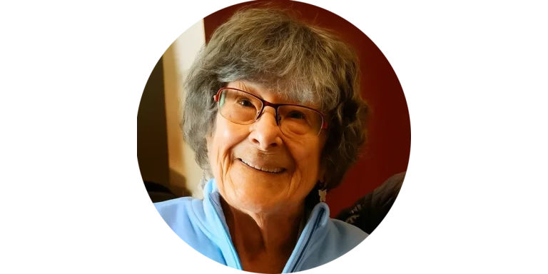 Lächelnde Seniorin – Erinnerung an eine liebe Kundin von Mia Oppermann“ Lächelnde Seniorin mit Brille in blauer Jacke – eine liebe Kundin von Mia Oppermanns Seniorenassistenz.